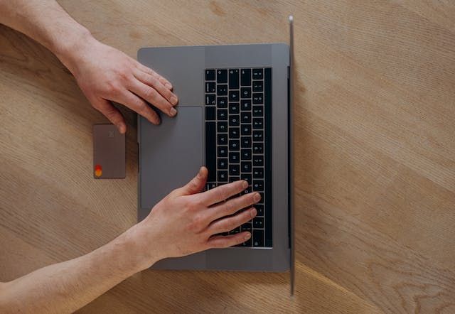 person holding a credit card while on their laptop