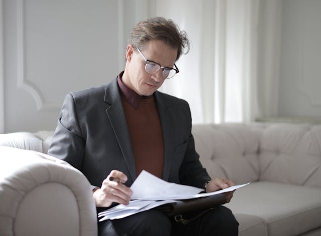 person reviewing a lease agreement while sitting on a couch