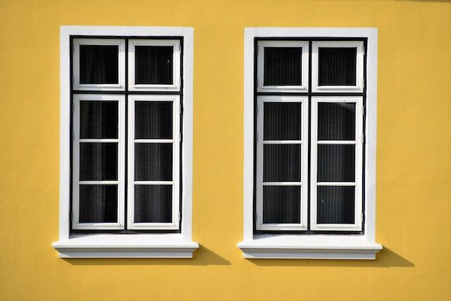 two windows on an exterior yellow wall