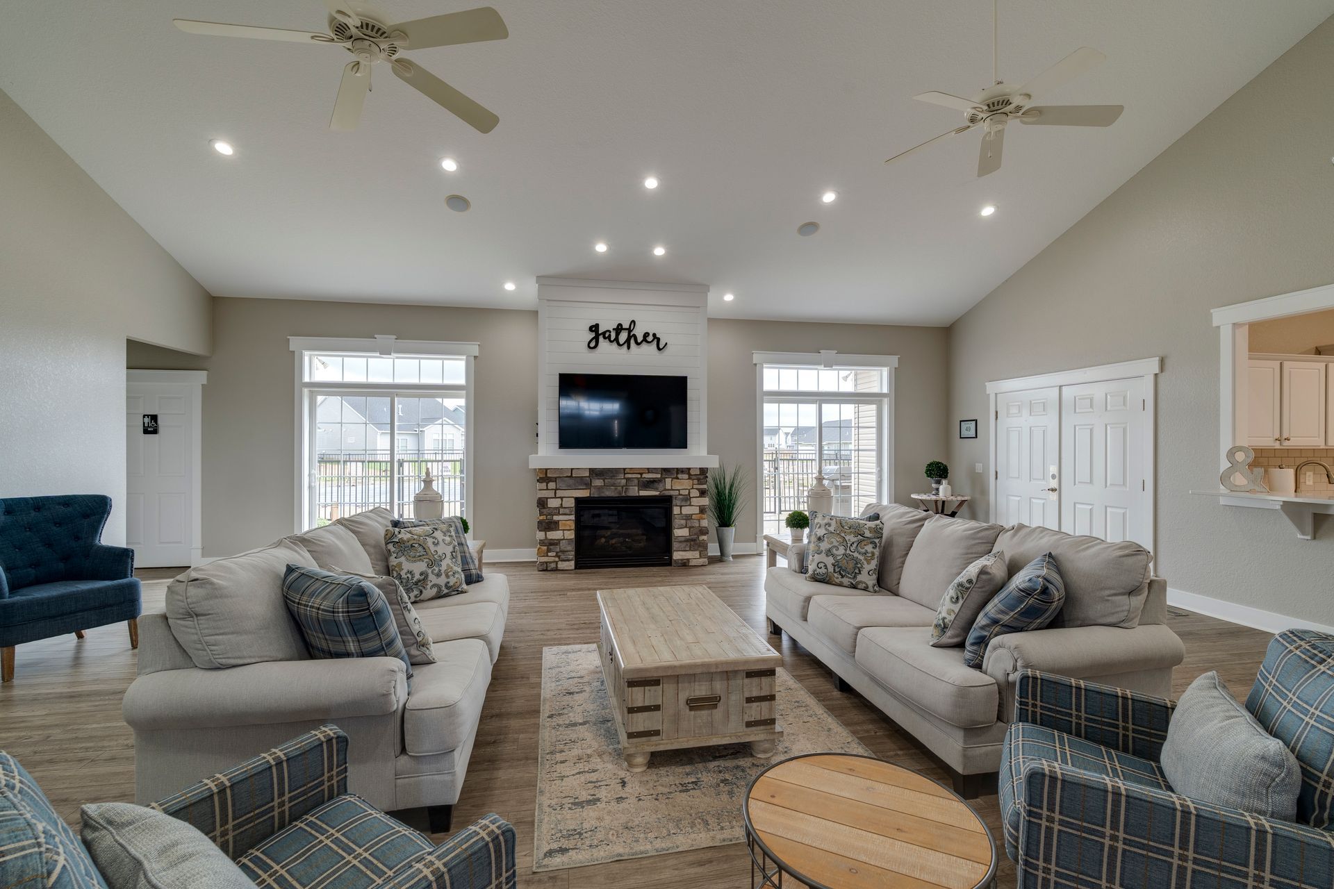 Living room with couches, fireplace, TV, and ceiling fans.