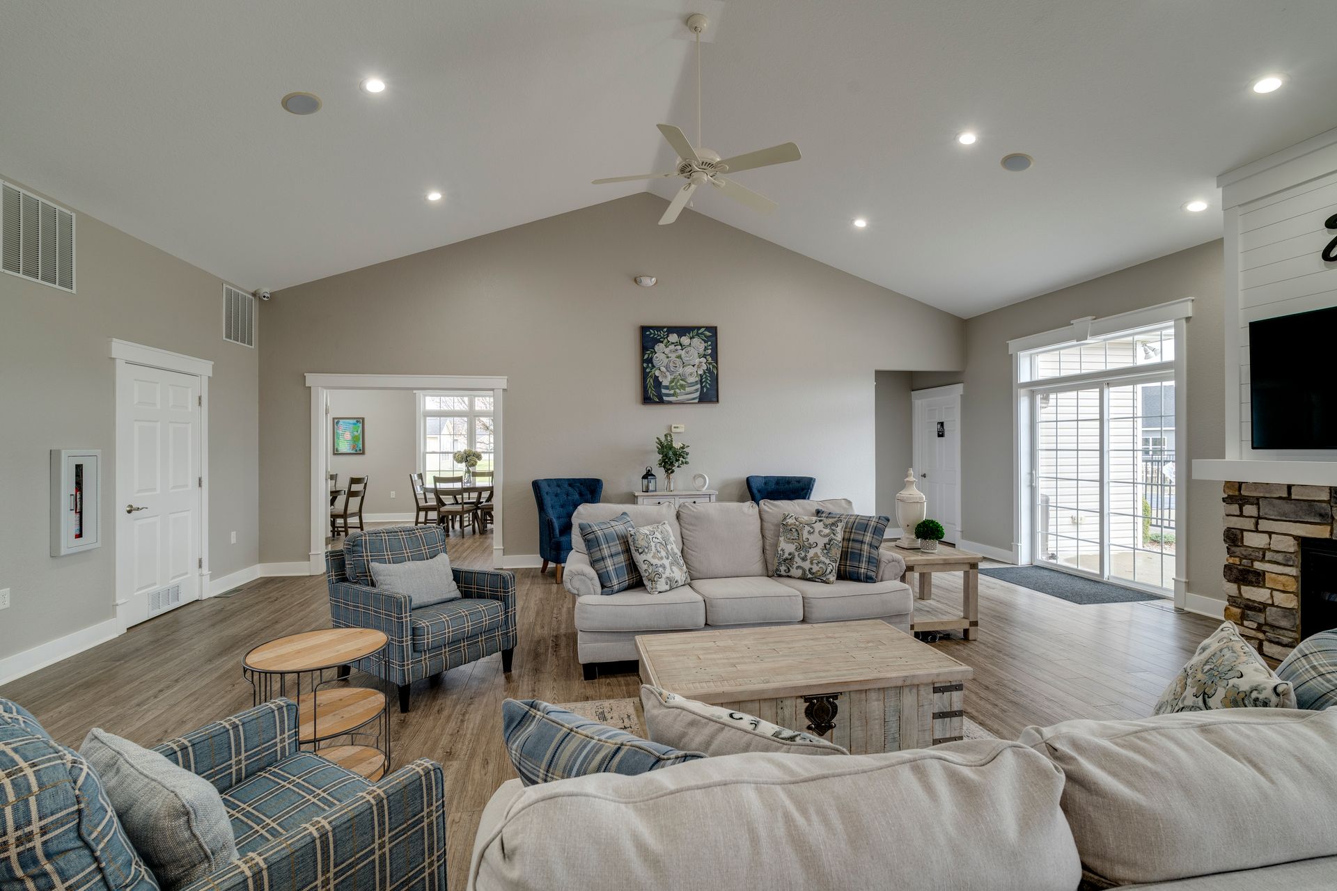 Spacious living room with vaulted ceiling, neutral tones, wood floors, couches, and armchairs.