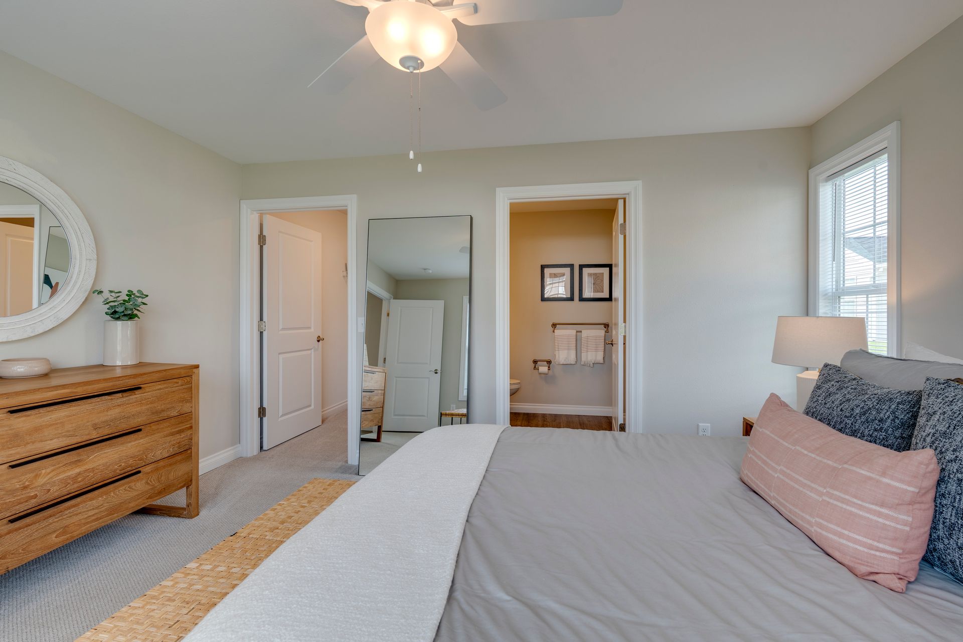Bedroom with bed, dresser, doors to bathroom and closet, and a ceiling fan.