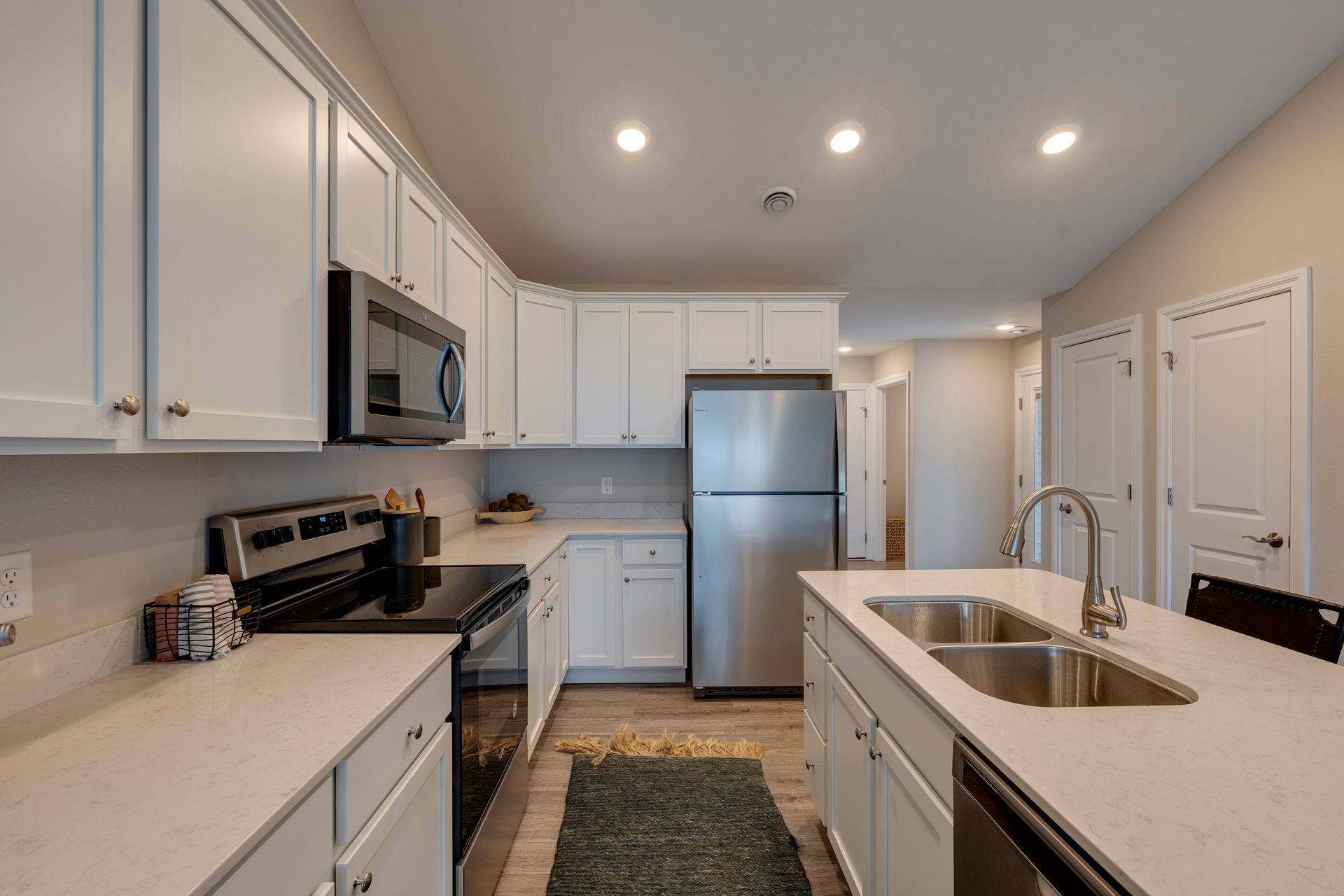 White kitchen with stainless steel appliances, white cabinets, and an island with a sink.