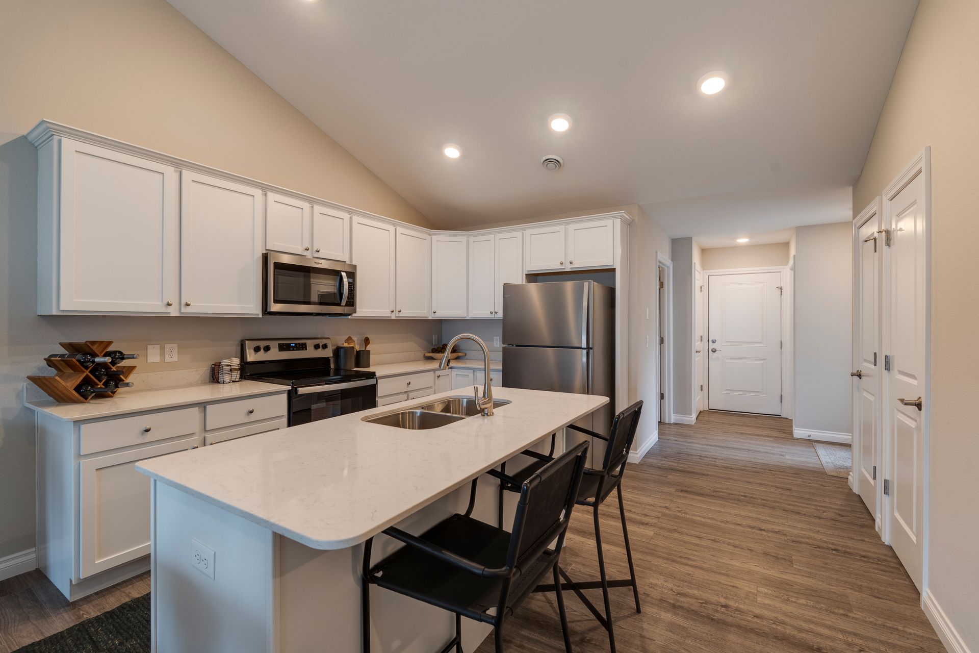 Modern kitchen with white cabinets, stainless steel appliances, and an island with bar stools.