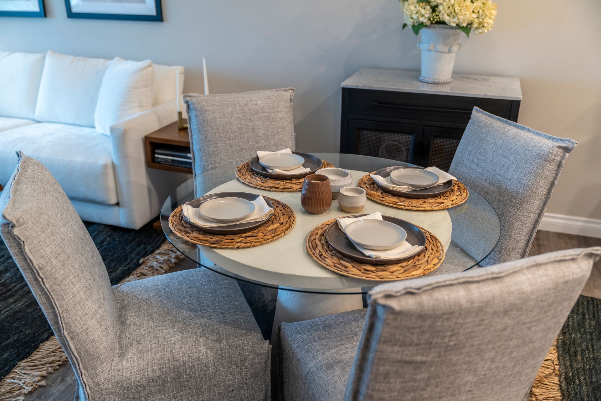 Round dining table set for four with plates, place mats, and chairs.