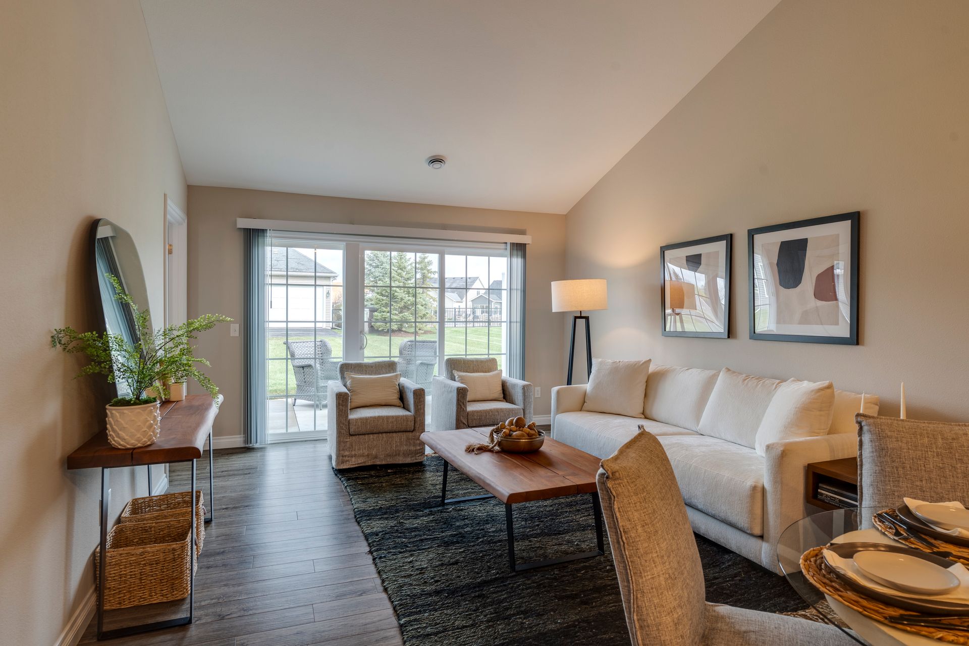 Living room with cream sofa, two armchairs, a coffee table, and a sliding glass door to a patio.