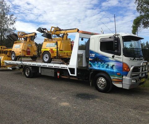 A White Truck Carrying A Large Equipment — DJ’s Tilt Tray Service in Urunga NSW