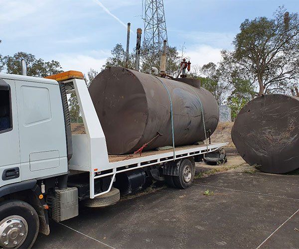 A Truck Carrying A Large Container — DJ’s Tilt Tray Service in Urunga NSW