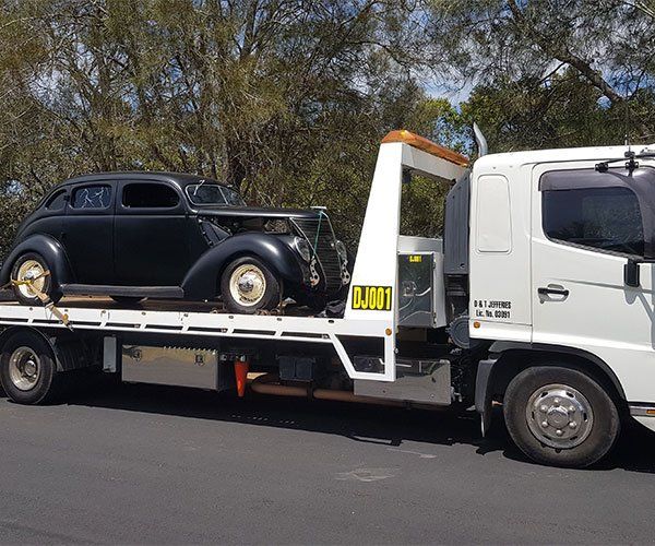 A Truck Carrying A Small Car — DJ’s Tilt Tray Service in Urunga NSW