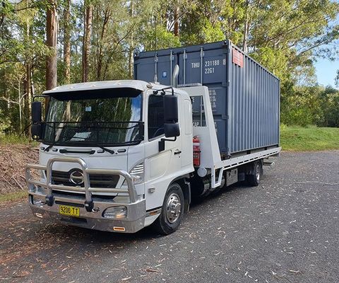 A Truck Carrying A Container — DJ’s Tilt Tray Service in Urunga NSW