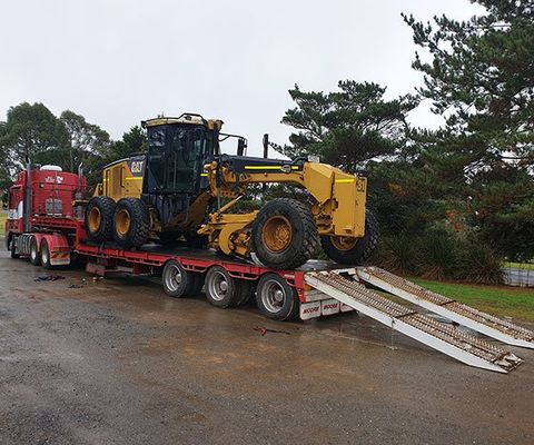 A Truck Carrying A Large Equipment — DJ’s Tilt Tray Service in Urunga NSW