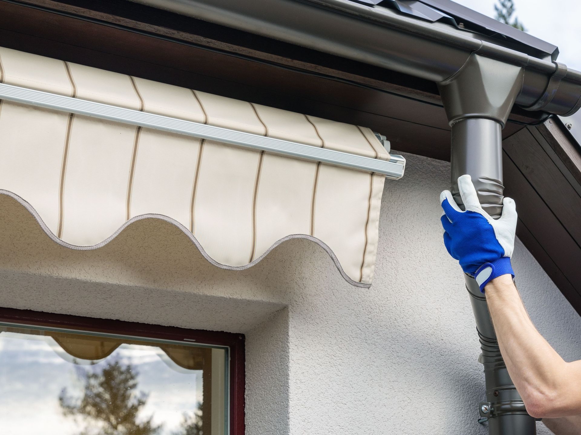 A person is installing an awning on the roof of a house.