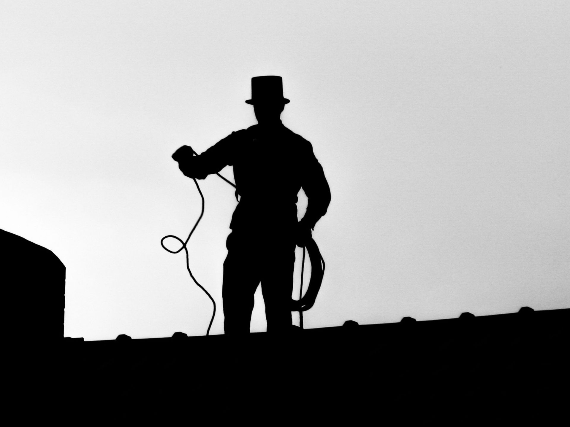 A silhouette of a man in a top hat holding a rope