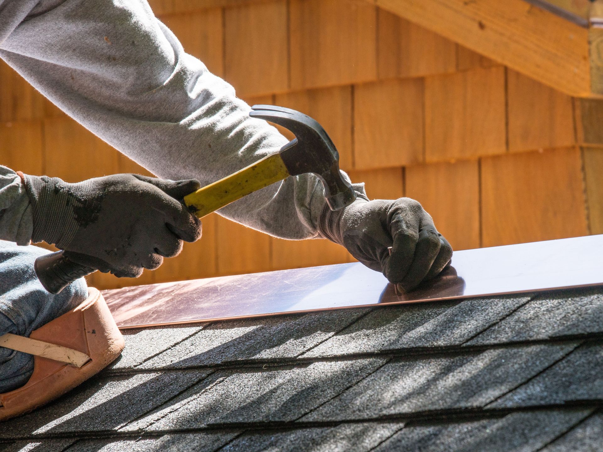 A man is working on a roof with a hammer.