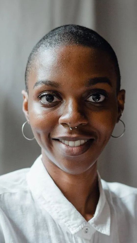 A woman with a nose ring and earrings is smiling for the camera.