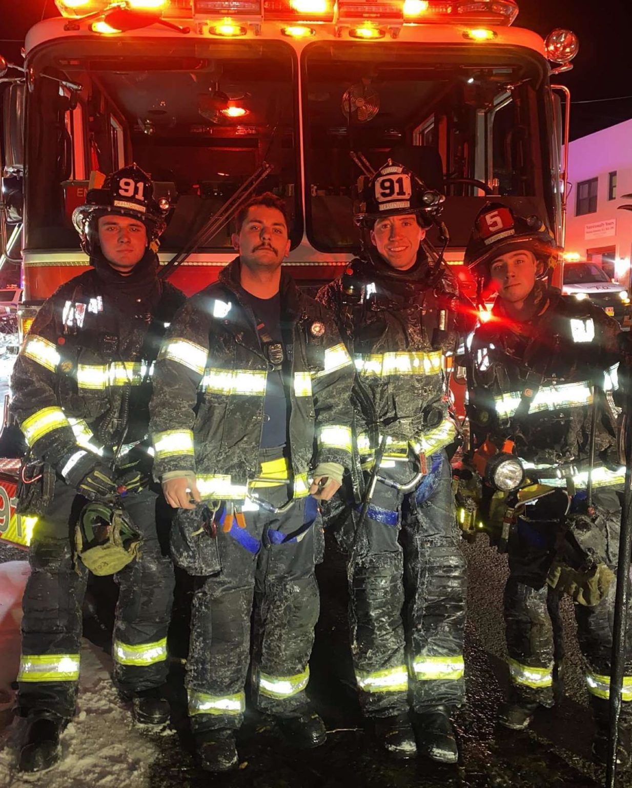 volunteer firefighters posed in front of truck at night