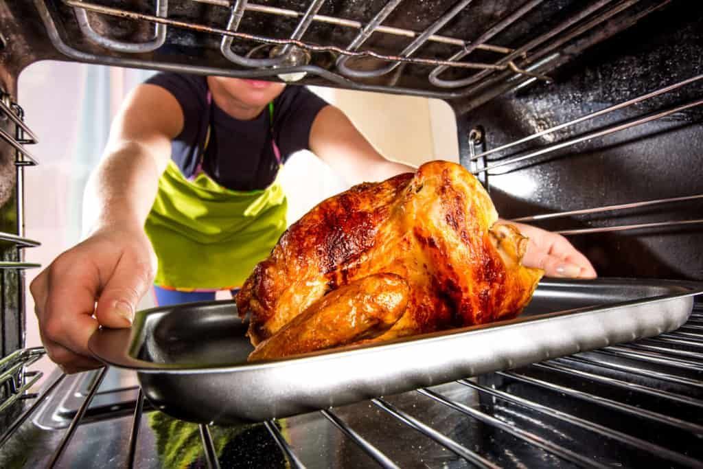 person taking turkey out of the oven
