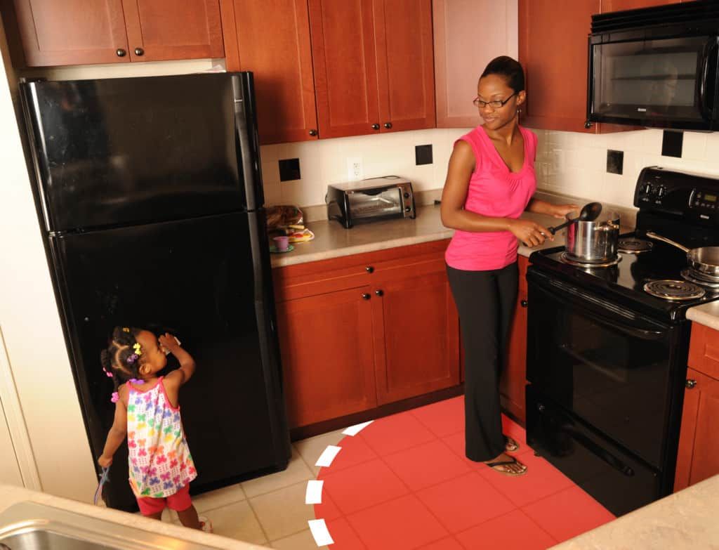 mother cooking at stove and child standing at least 3 feet away
