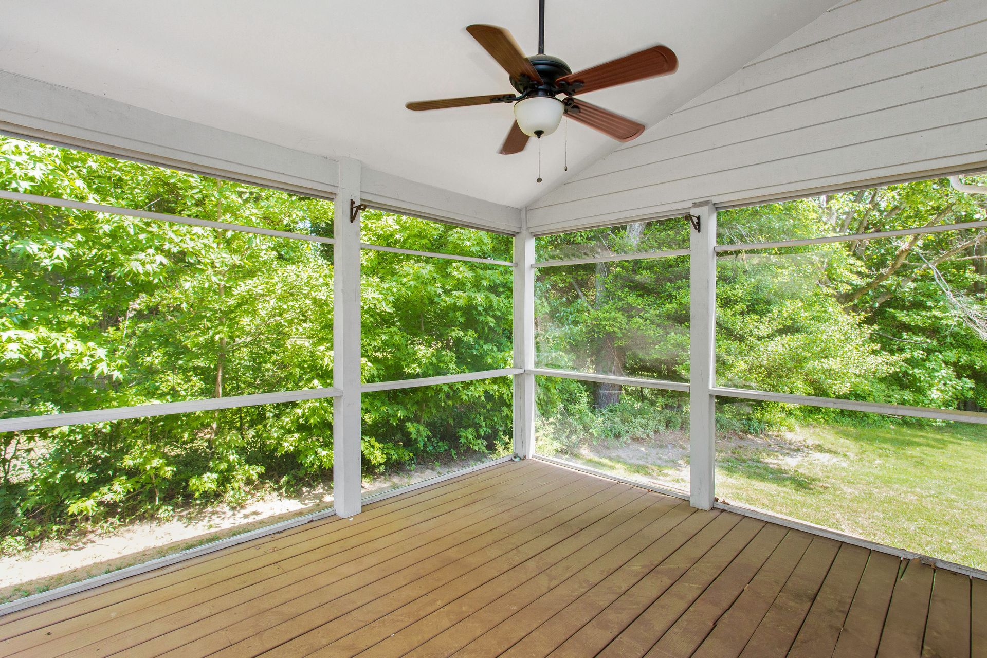Retractable screens on an enclosed patio with a ceiling fan in a home during summertime 
