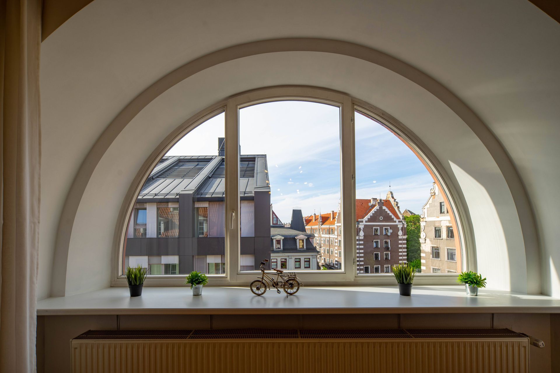 A semi-circle window, without custom blinds yet, inside a home that overlooks city buildings at Alto