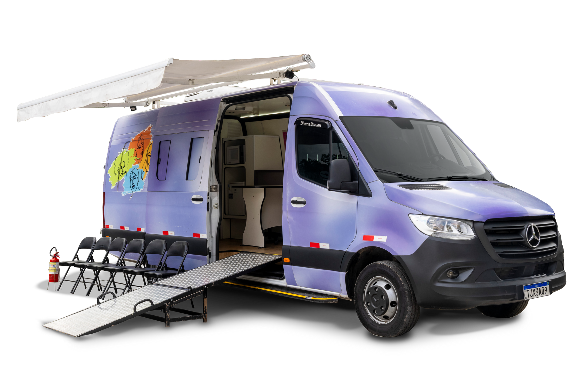 Clínica médica móvel azul com porta aberta, rampa e toldo, estacionada ao ar livre.