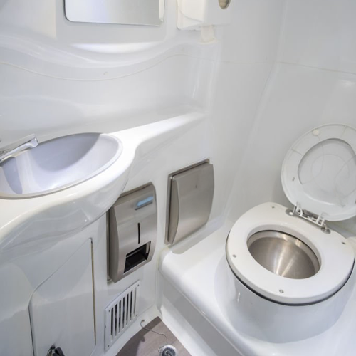 Banheiro de barco branco e luminoso com pia e vaso sanitário.