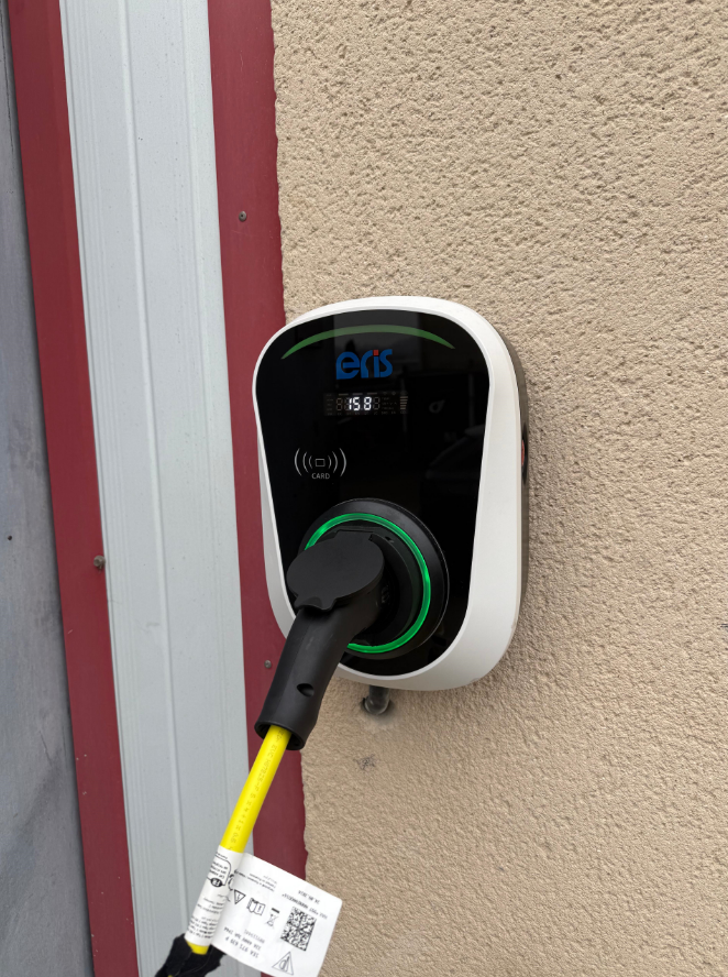 Une voiture électrique est en cours de recharge sur une borne de recharge située sur le côté d'un bâtiment.