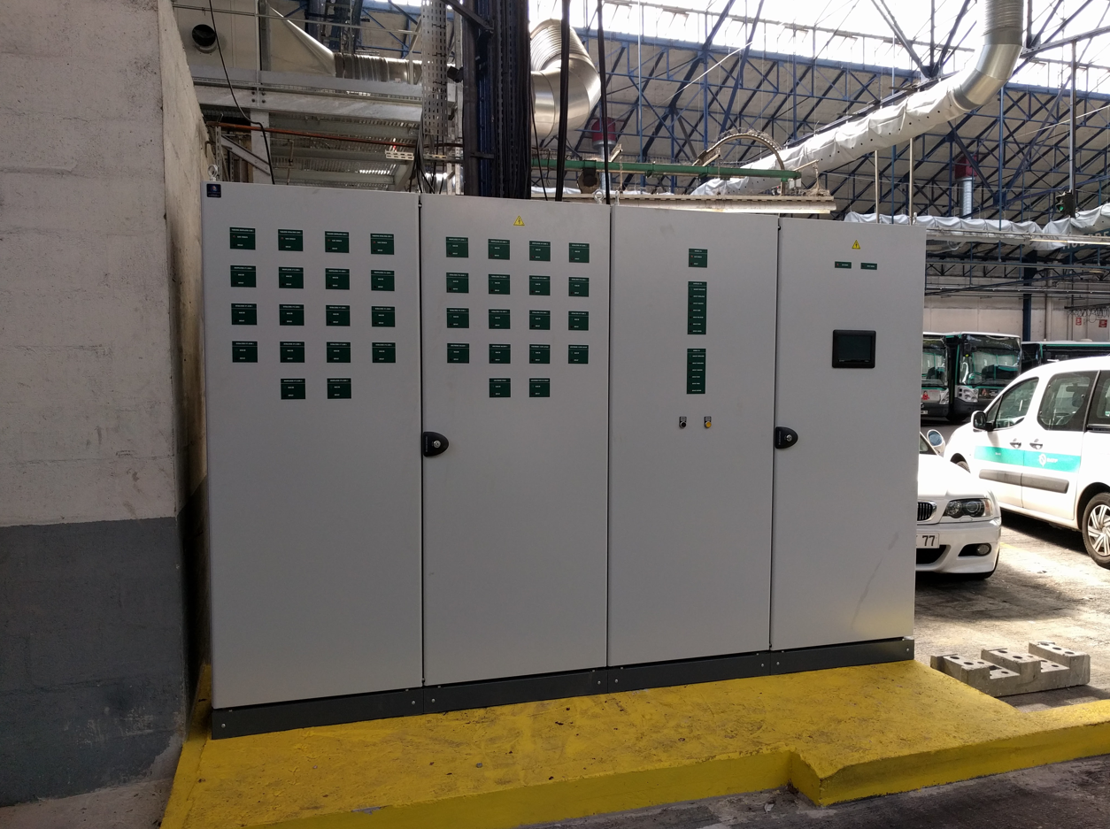 Une boîte blanche avec des carrés dessus est posée sur une plate-forme jaune à côté d'un bâtiment.