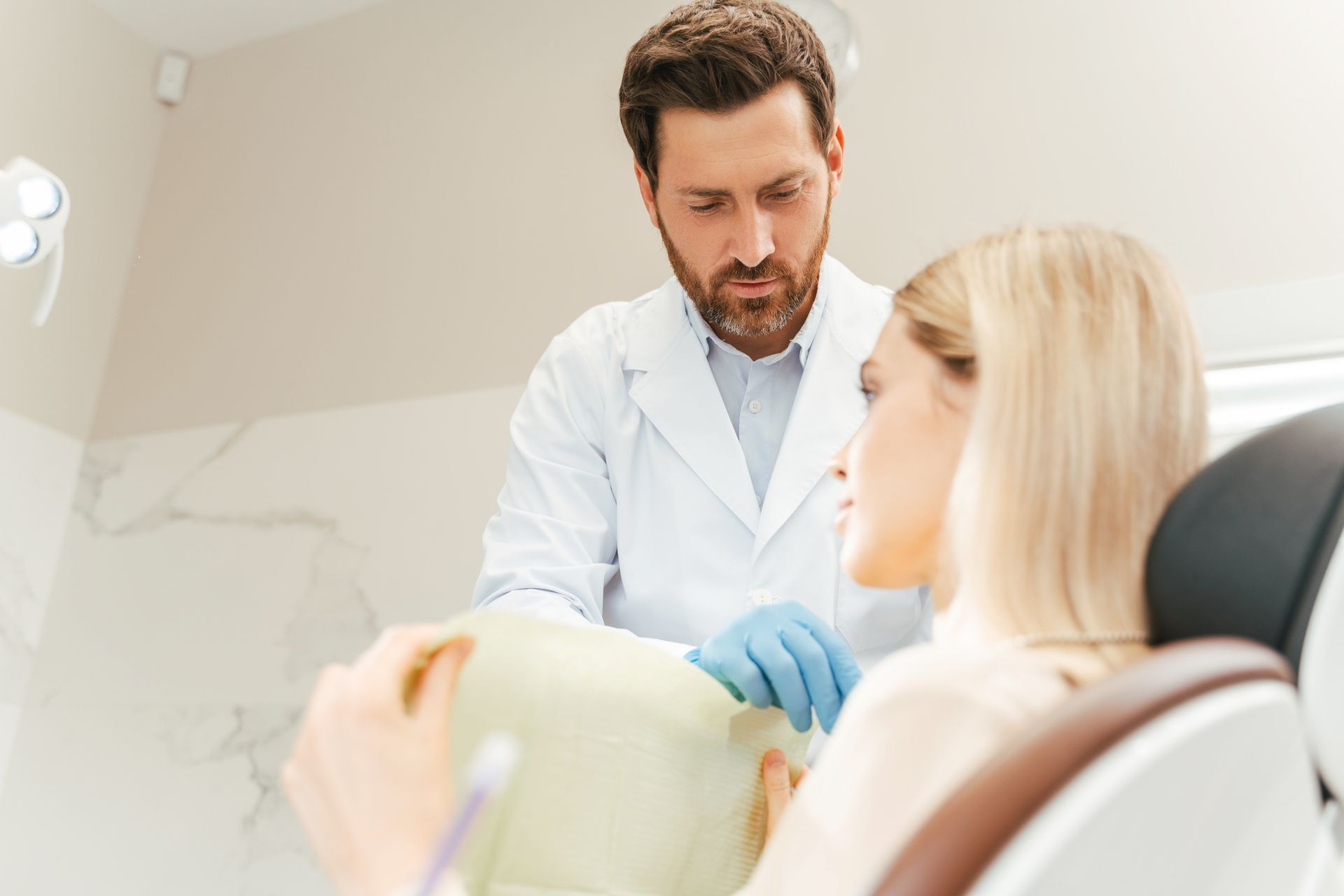 Dentist showing teeth whitening shade guide to smiling woman in clinic. Dentist showing teeth whitening shade guide to smiling woman in clinic.