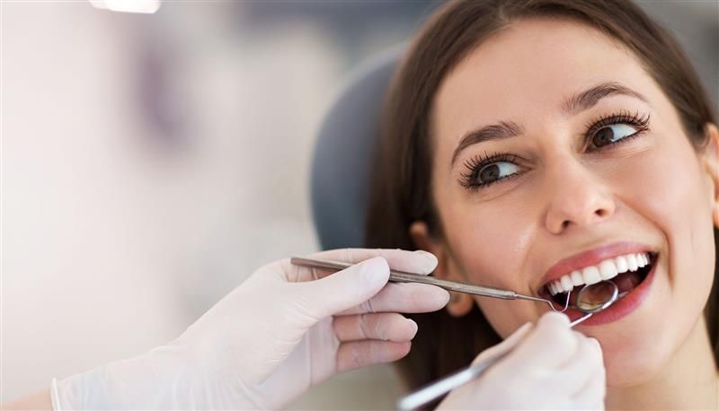 Dental professional using medical tool during oral examination in a modern dental clinic setting.