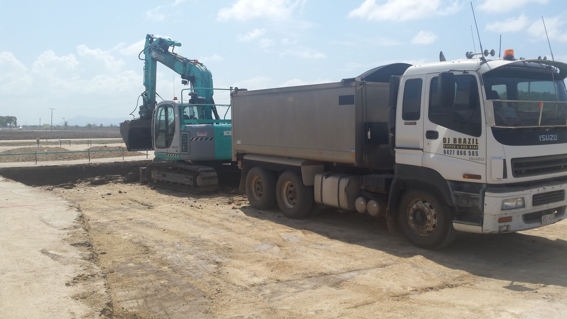an Excavator Loads Dirt Into a Dump Truck on a Construction Site — DJ Brazil Pty Ltd in Bowen, QLD