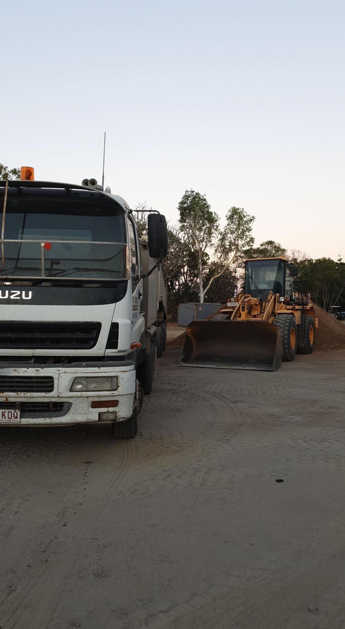 White Isuzu Truck Next to a Yellow Front-end Loader on a Dirt Lot — DJ Brazil Pty Ltd in Bowen, QLD