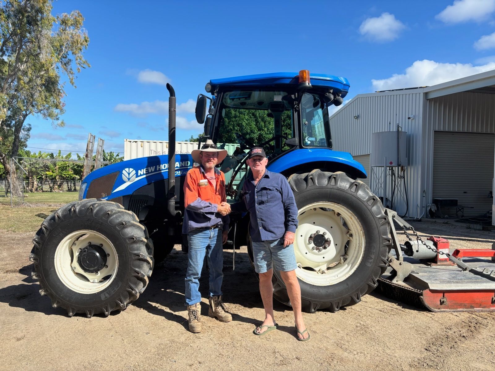 Two Men Shaking Hands Beside a Blue Tractor on a Farm on a Sunny Day — DJ Brazil Pty Ltd in Bowen, QLD
