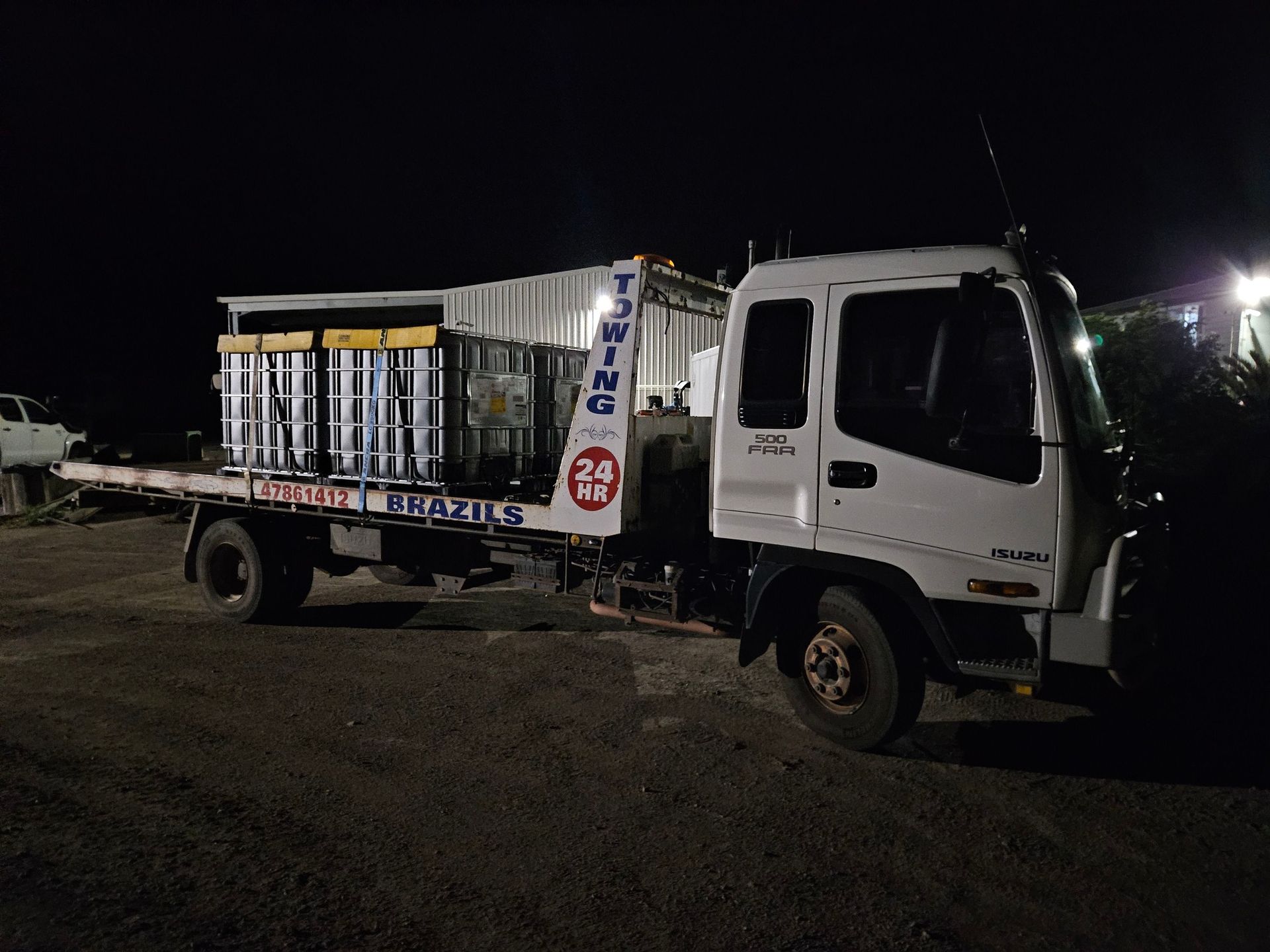 White truck with cargo bed at night, hauling large containers  - DJ Brazil earthmoving, truck and tilt tray hire, Bowen QLD