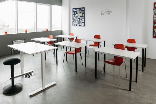 A classroom with white tables and red chairs