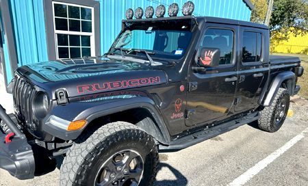 Black Jeep Gladiator Rubicon with off-road lights, parked outdoors.