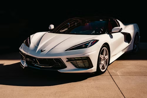 White sports car parked at night on a dimly lit pavement