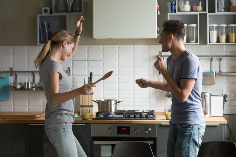 A Man and a Woman Are Dancing in the Kitchen While Cooking — Border Pest Control In Wagga Wagga, NSW