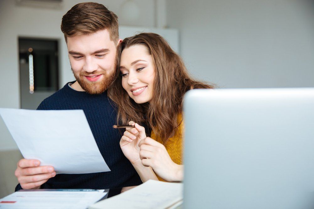 A Man and a Woman Are Sitting at a Table Looking at a Laptop and a Piece of Paper — Border Pest Control In Wodonga, VIC