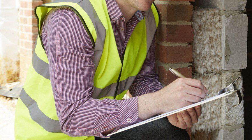 A Man in a Yellow Vest is Writing on a Clipboard — Border Pest Control In Albury, NSW