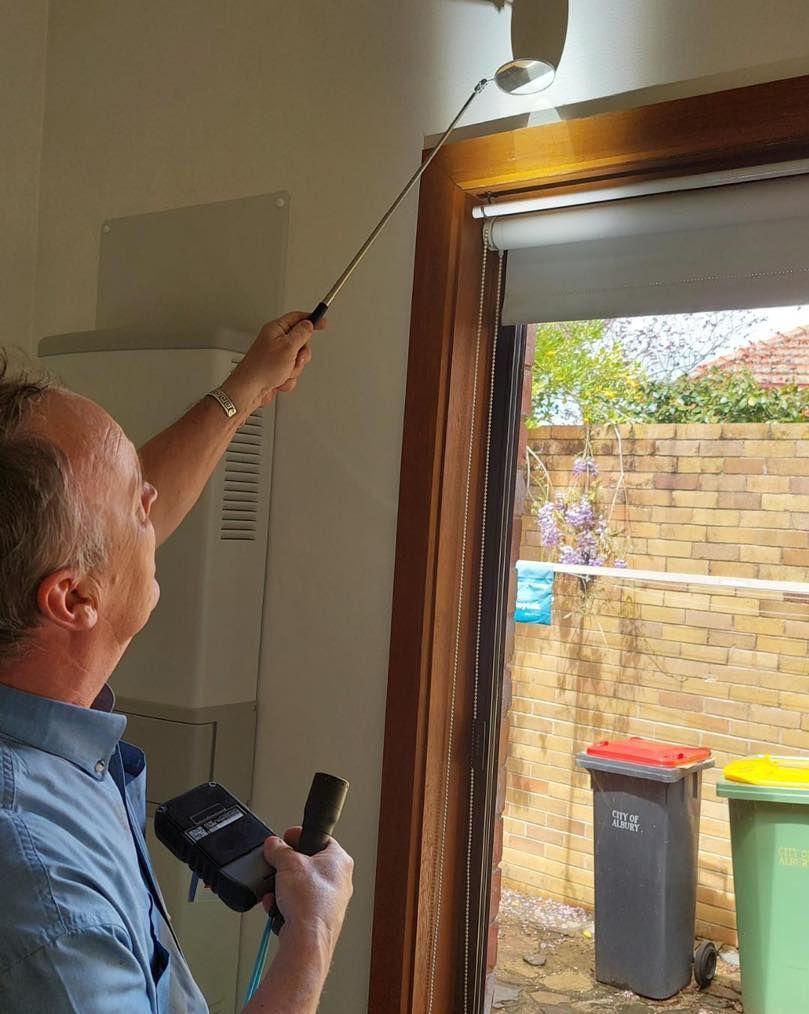 A Man is Looking Through a Window With a Flashlight — Border Pest Control In Albury, NSW
