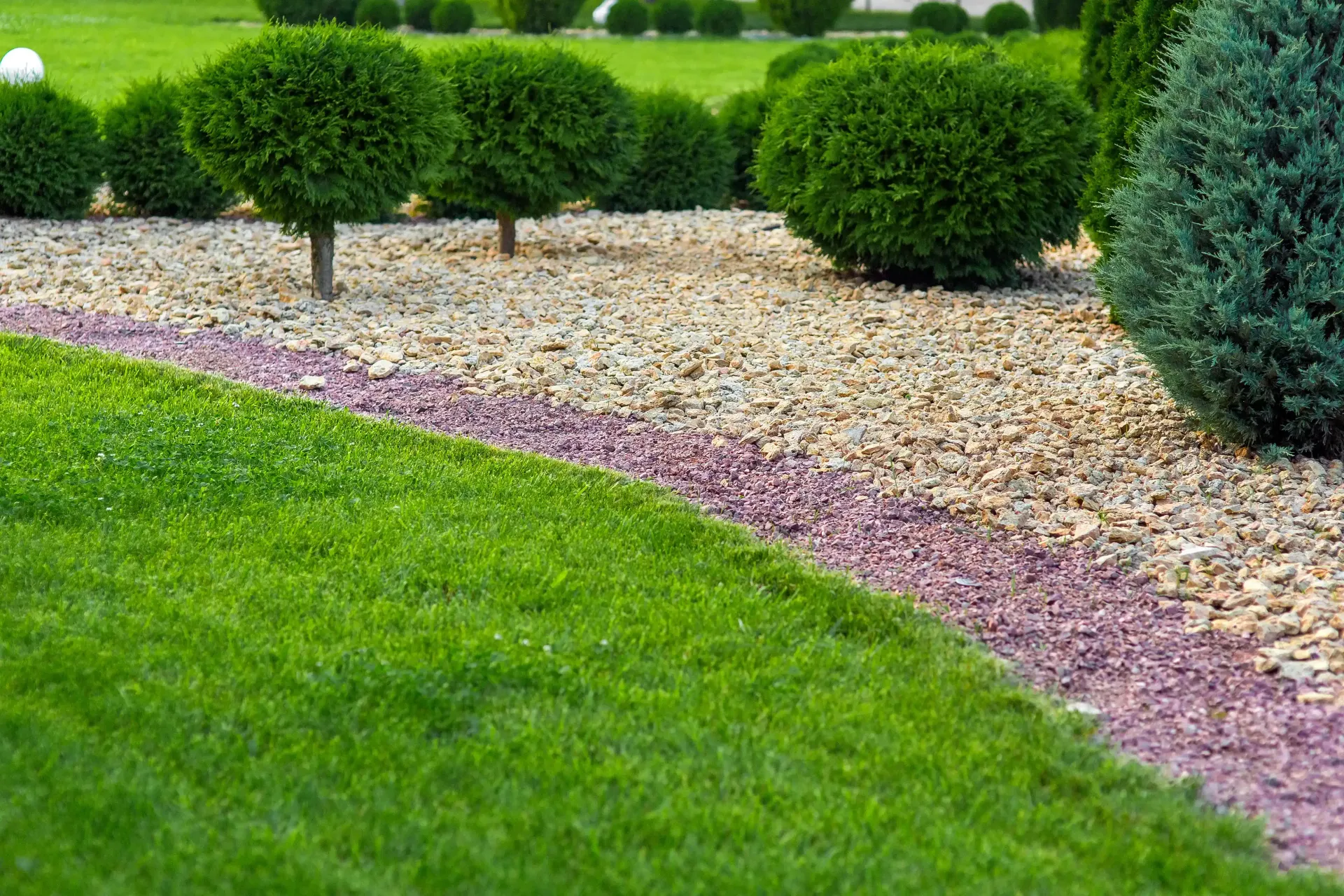 trimmed grass, mulch and rocks with shrubs in the background