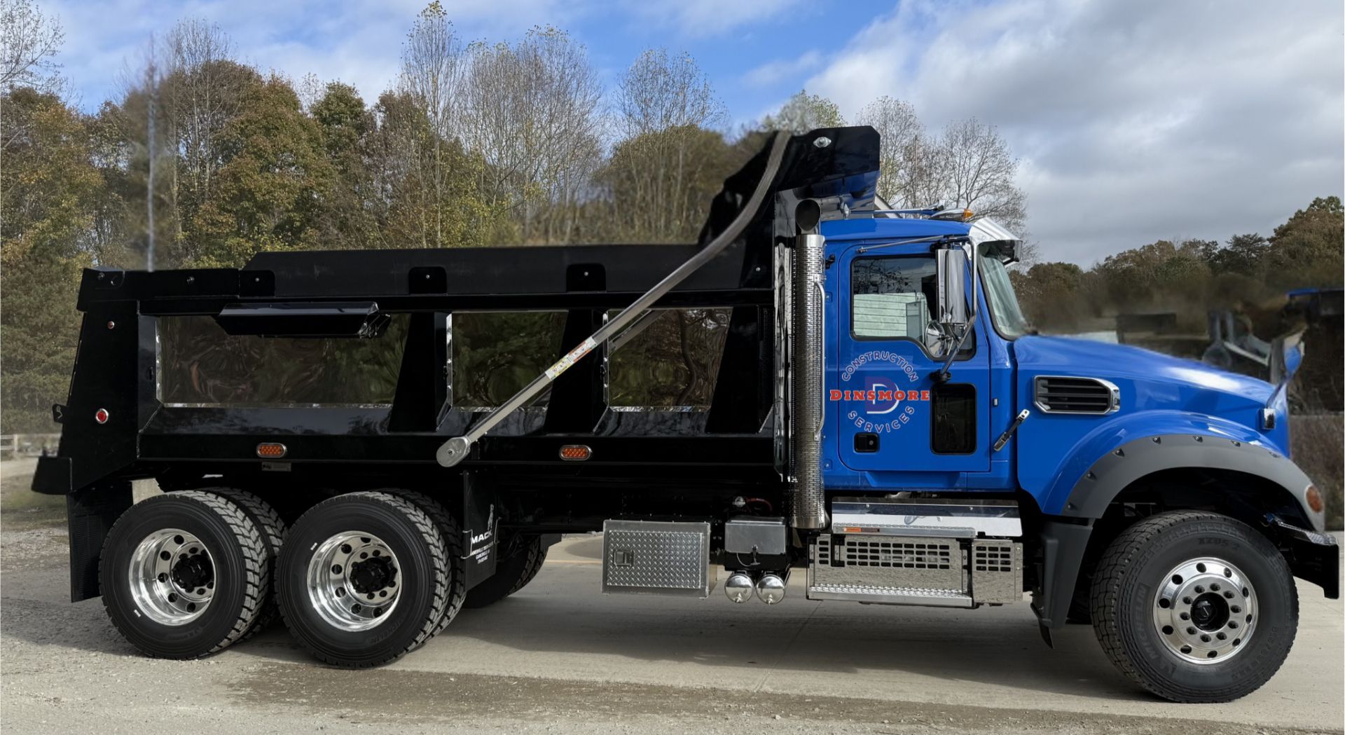 Blue dump truck with black bed, parked outdoors.