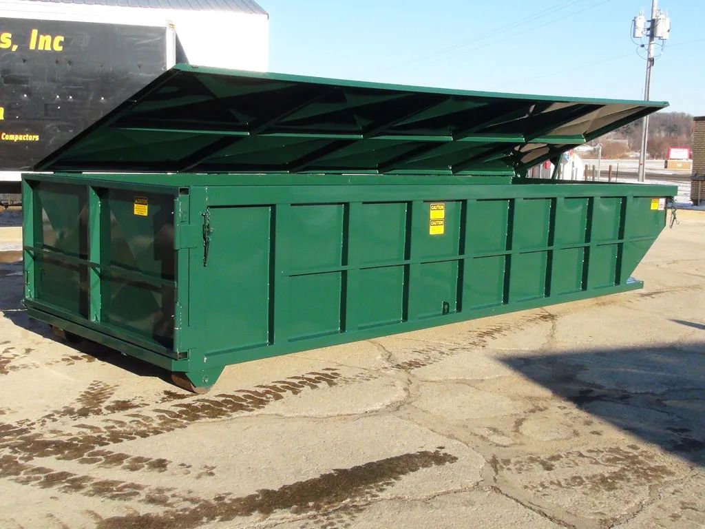 Green industrial dumpster with open lid on concrete.