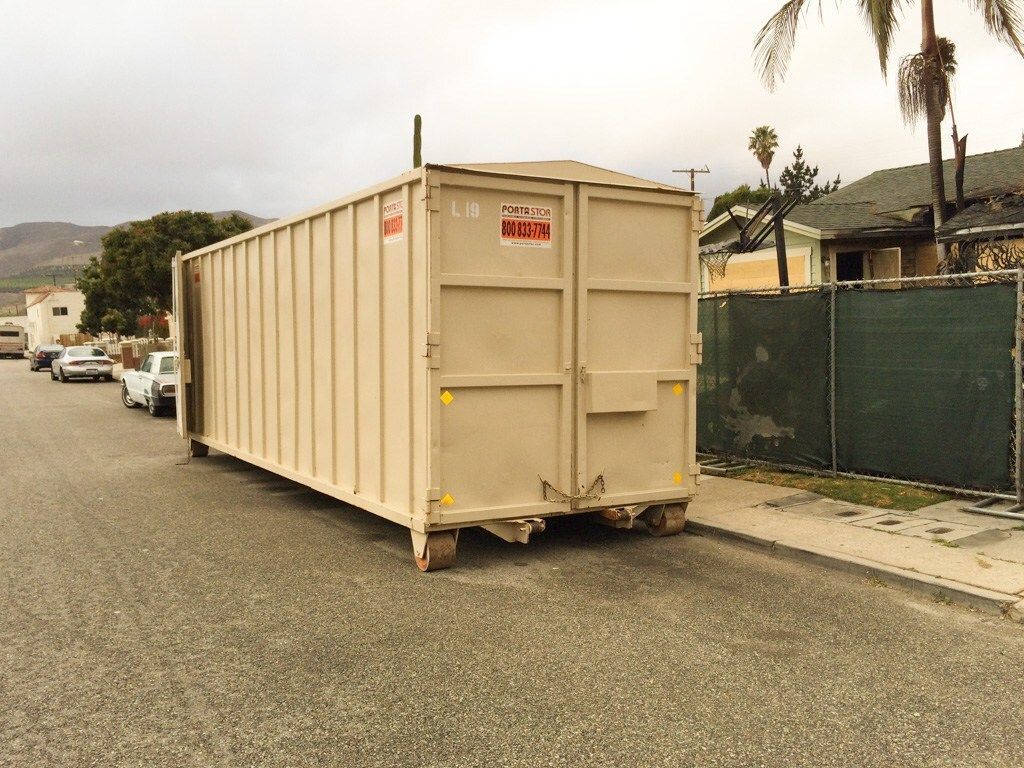 Tan shipping container parked on a residential street.