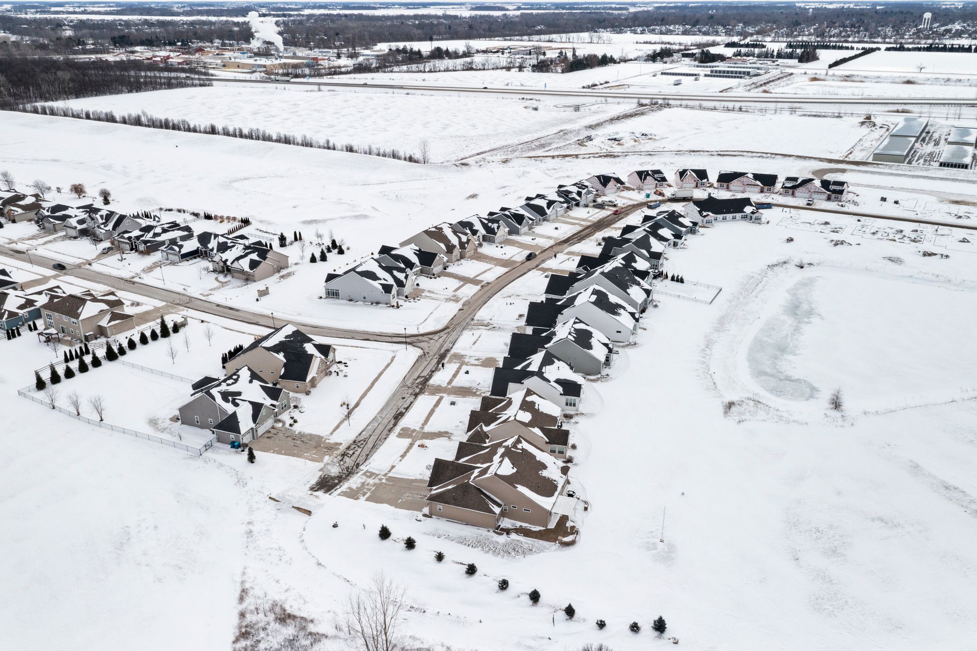 Aerial view of a snow-covered suburban neighborhood with houses and roads.