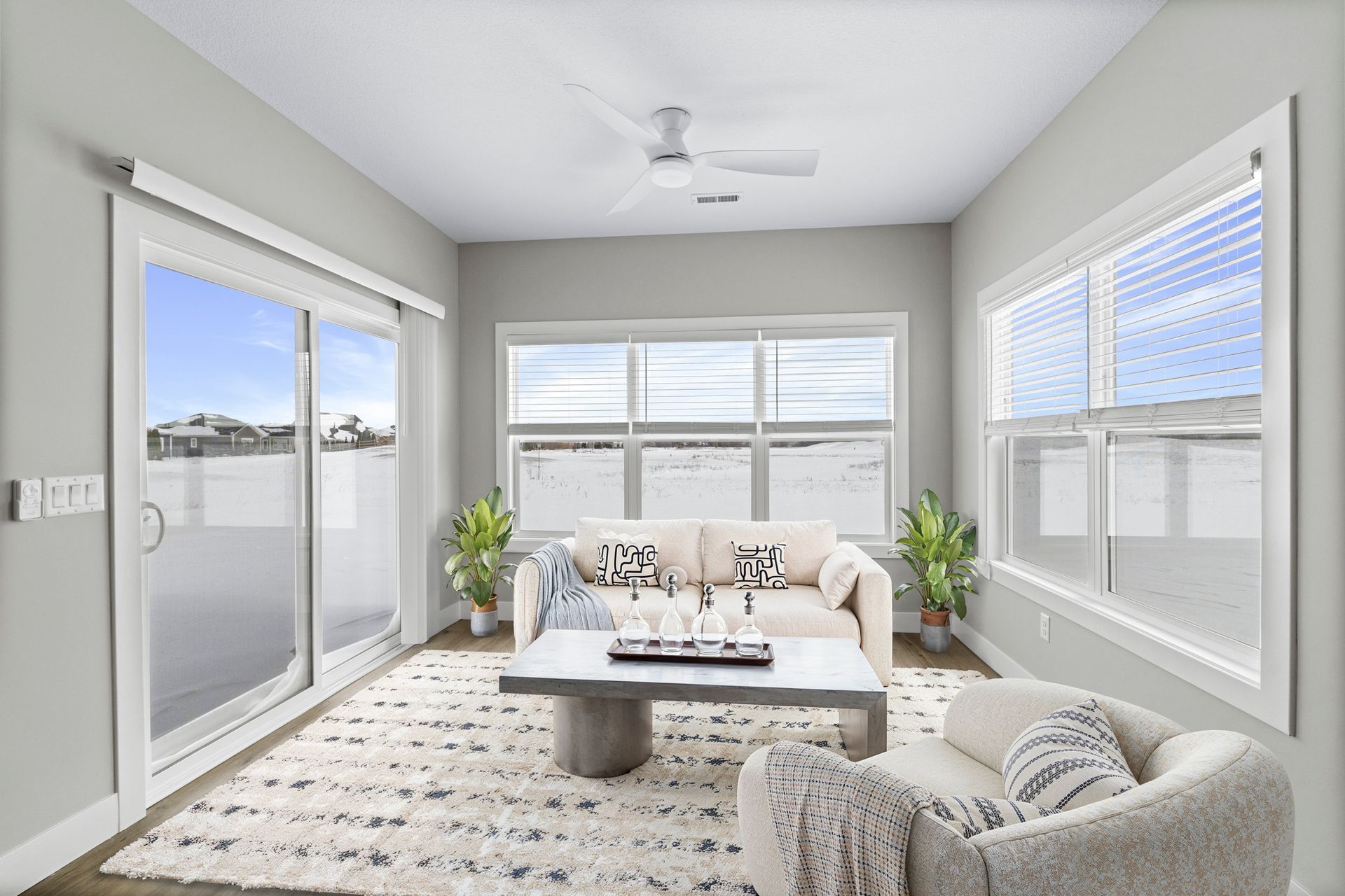 Living room with large windows, sliding glass door, neutral decor, and fluffy rug.