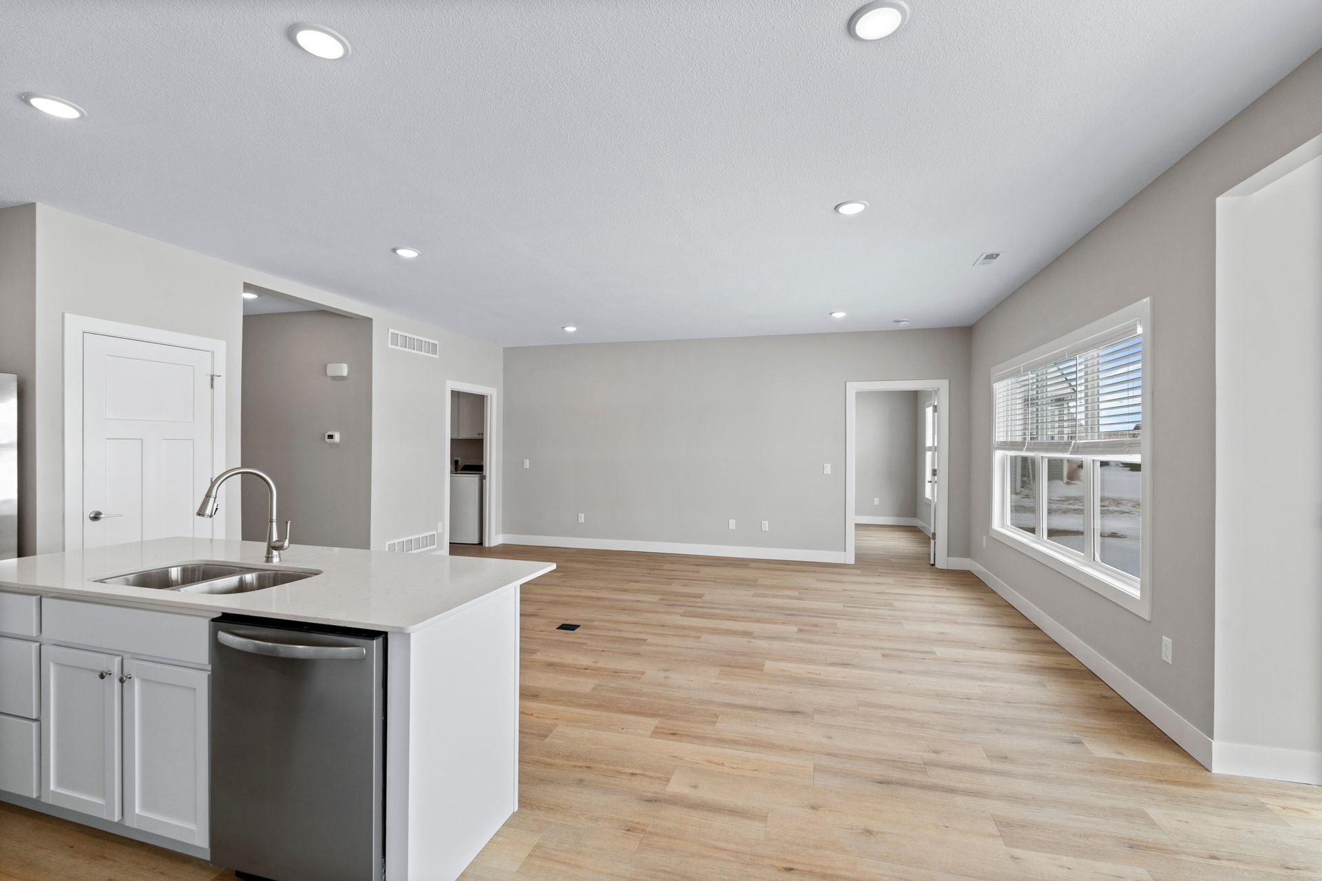 Modern kitchen with white cabinets, stainless steel appliances, and light wood floors.