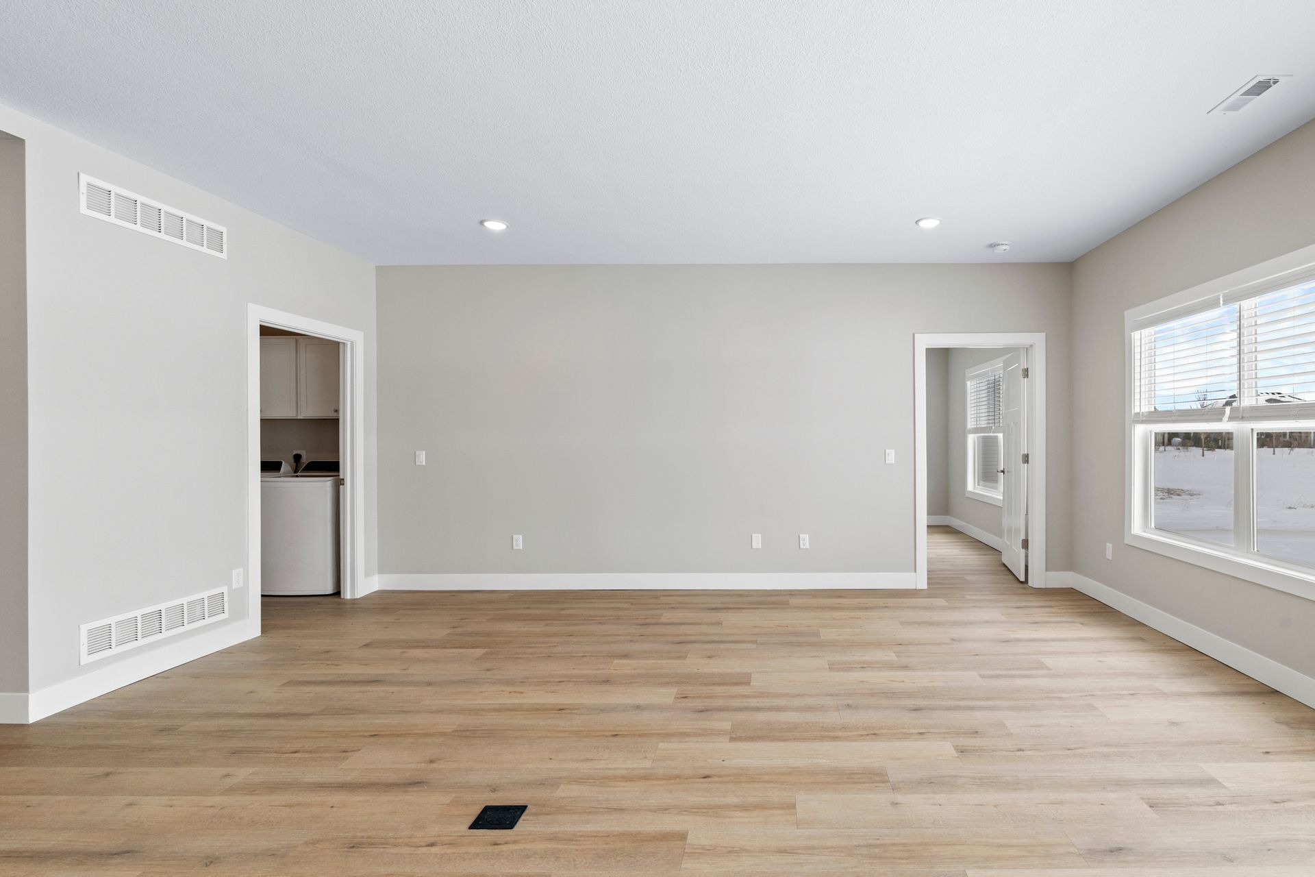 Empty room with light wood floors, white walls, and a window.