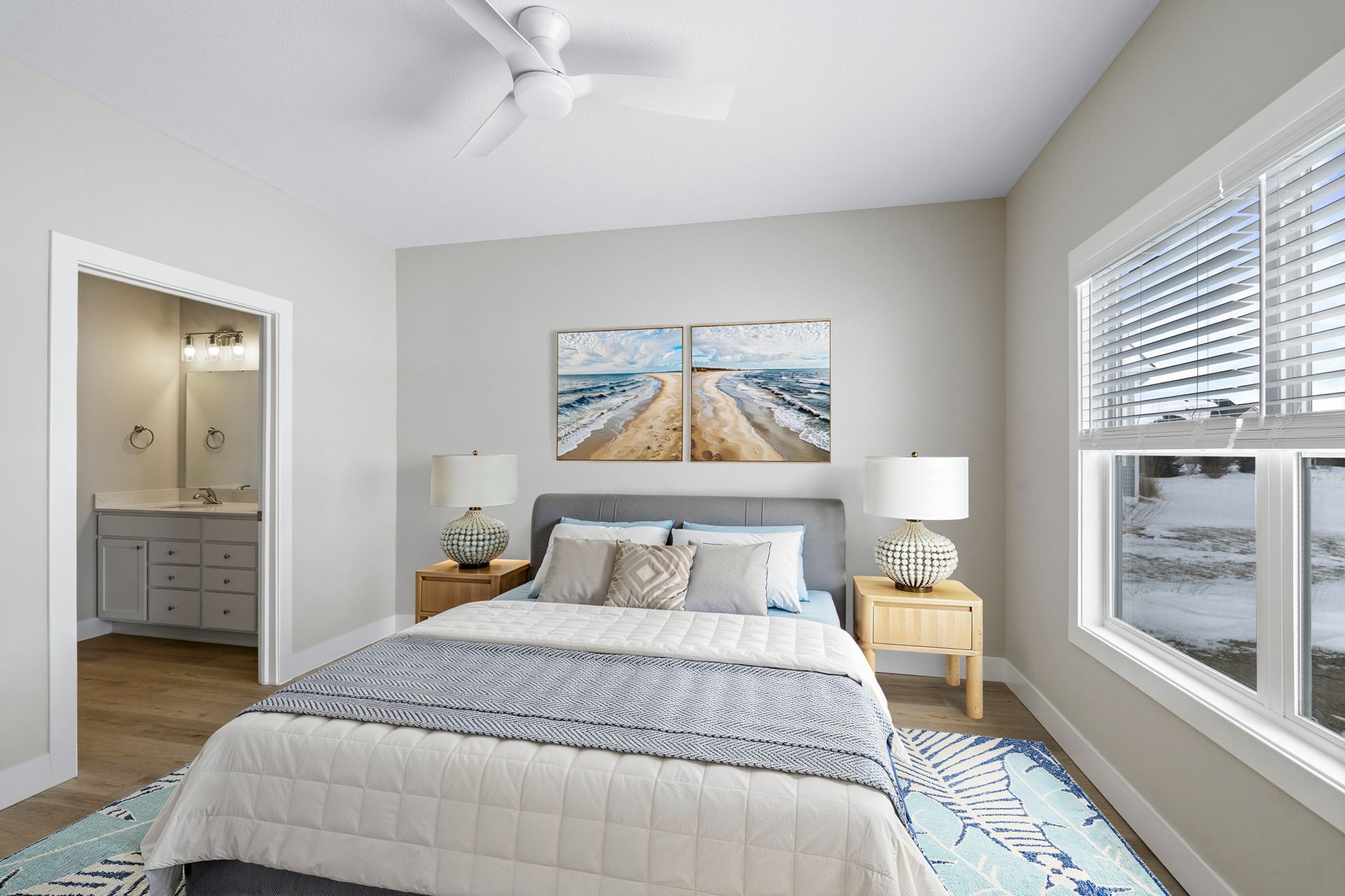 Bedroom with bed, nightstands, artwork, and view of a bathroom. Neutral colors, natural light.